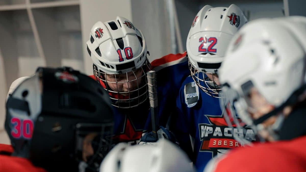 Teen hockey players in locker room getting ready, showcasing teamwork and team spirit.
