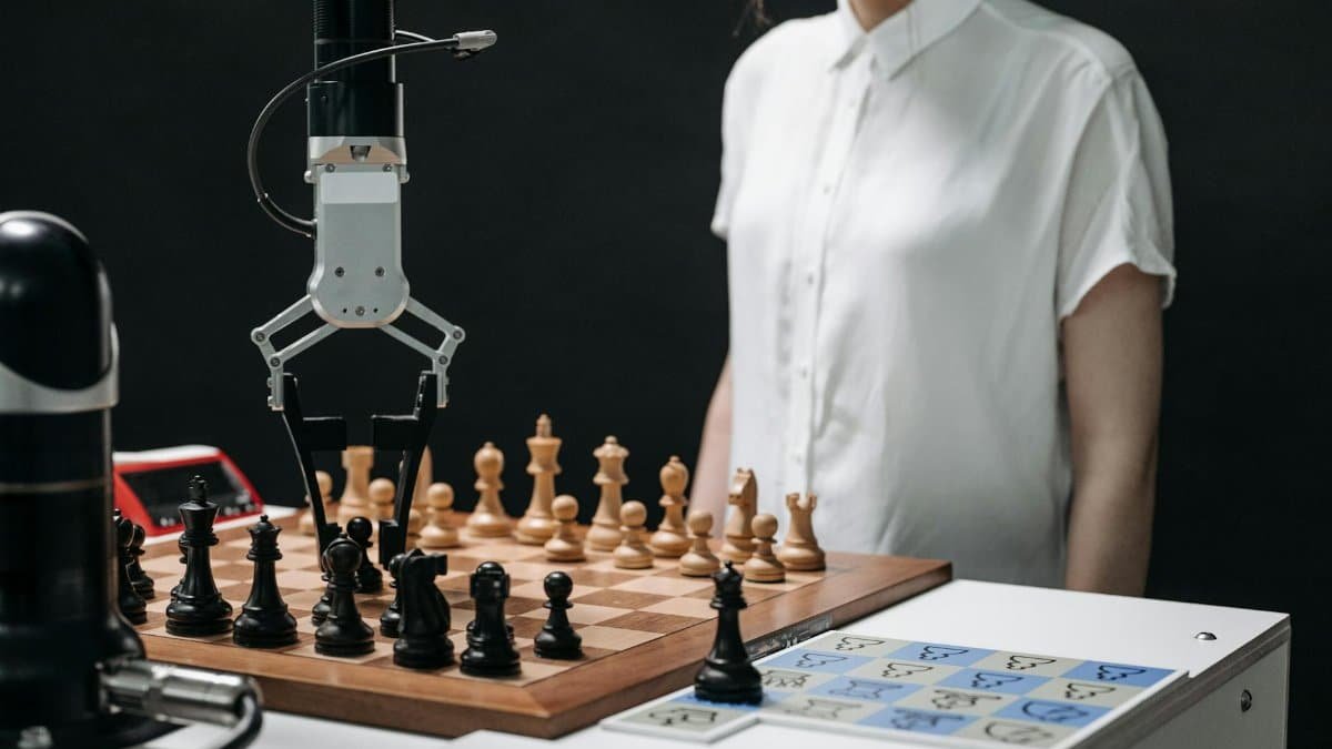 A robotic arm and a person engaged in a strategic chess match on a chessboard.