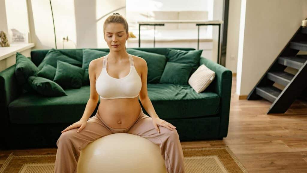 Expectant mother meditating on gym ball indoors for a healthy lifestyle.