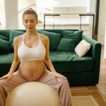 Expectant mother meditating on gym ball indoors for a healthy lifestyle.