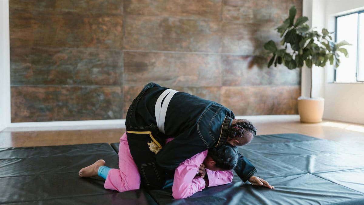 Two martial artists practicing grappling techniques indoors on a mat, emphasizing sportsmanship and training.