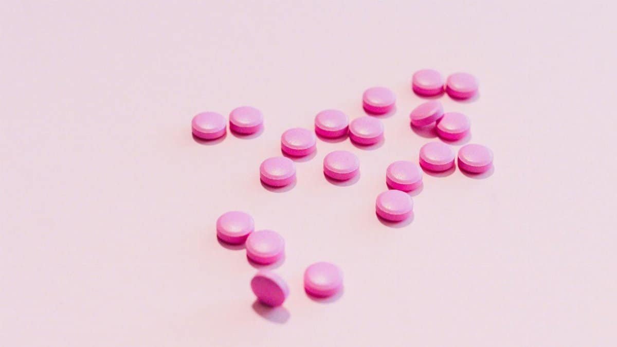 Close-up of pink pills scattered on a white surface, ideal for healthcare themes.