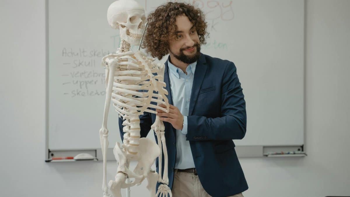 A biology teacher demonstrates the human skeleton model in an engaging classroom setting.