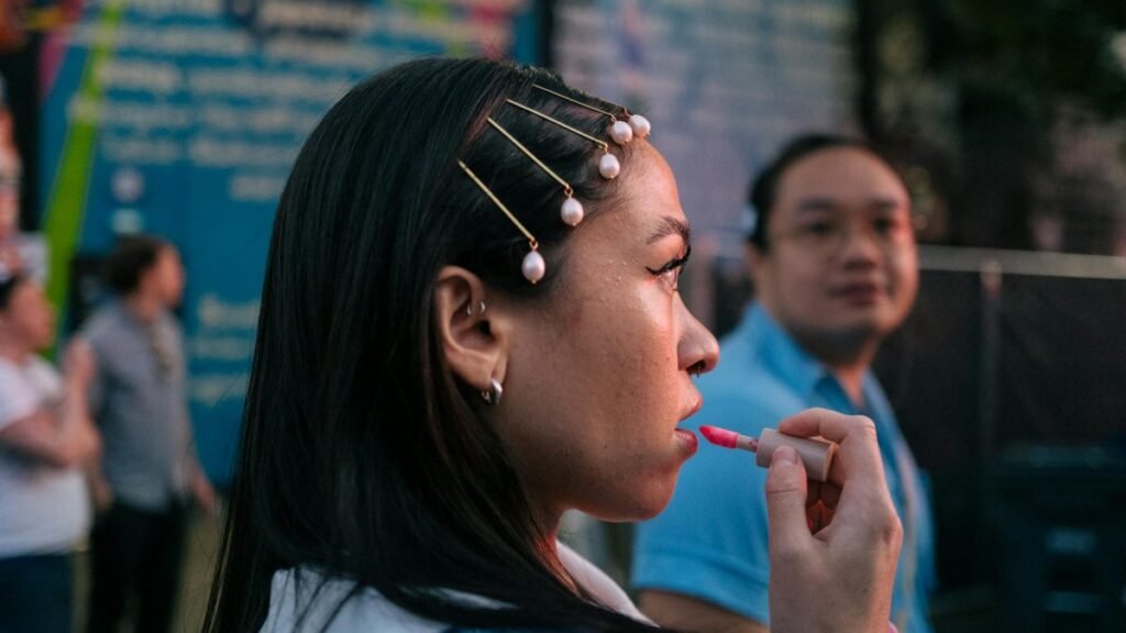 Profile view of an Asian woman applying lip gloss in an urban setting, Seattle.