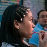 Profile view of an Asian woman applying lip gloss in an urban setting, Seattle.