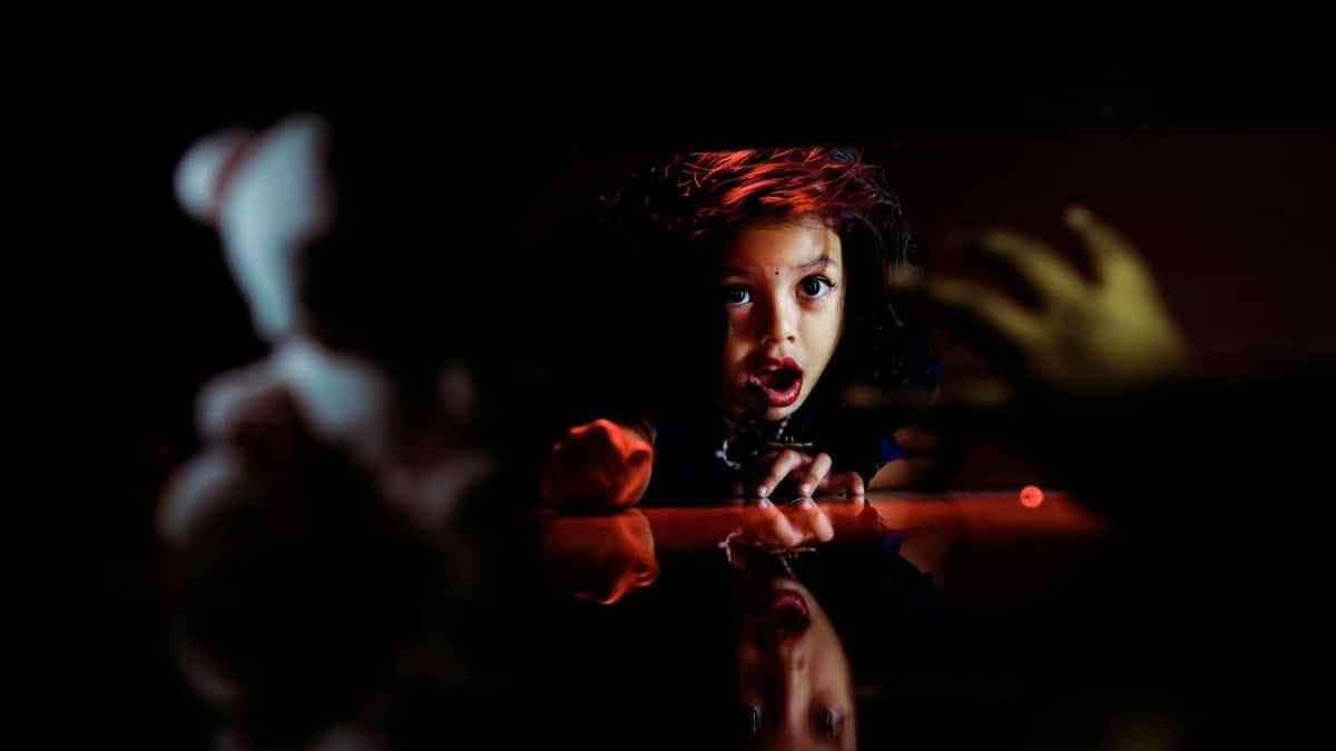 A child looks surprised while hiding, creating a dramatic moment of curiosity and play.