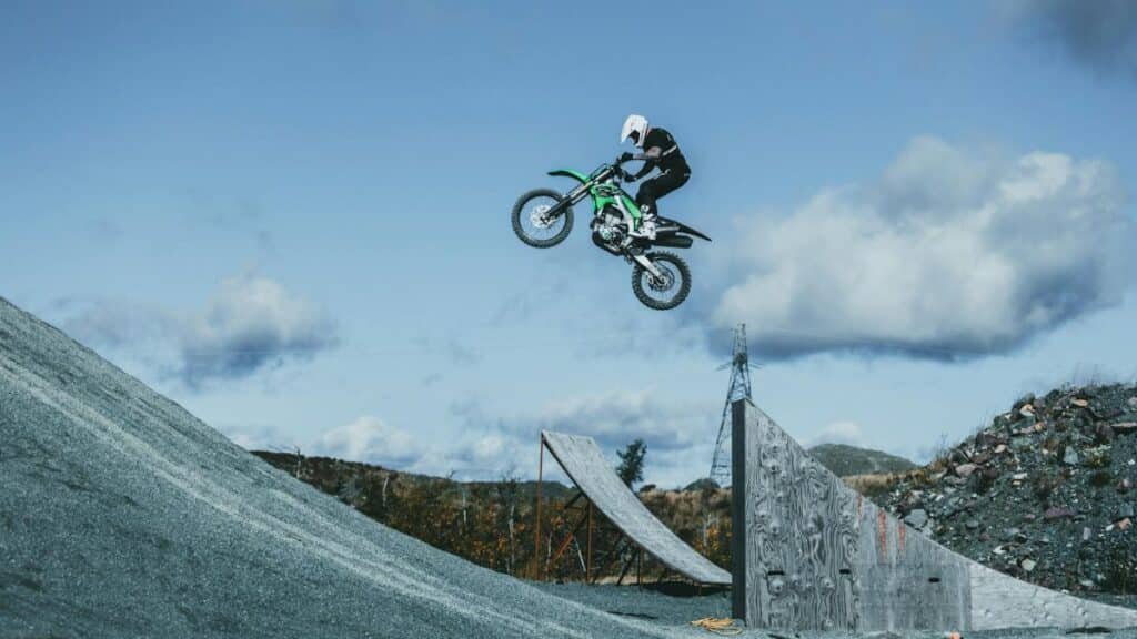 Motorcyclist performs high jump at motocross event in outdoor setting.