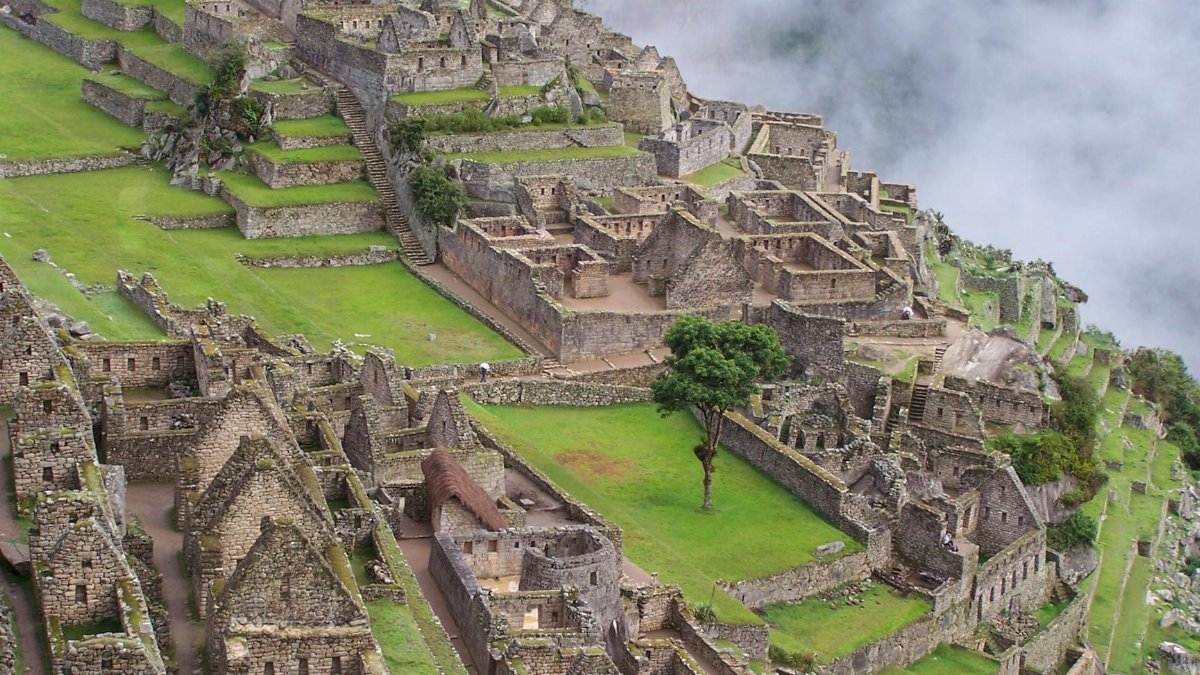 High-angle view of ancient Machu Picchu in misty atmosphere highlighting stone structures.