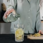 Woman pours water for lemon ginger infusion, promoting health and hydration.