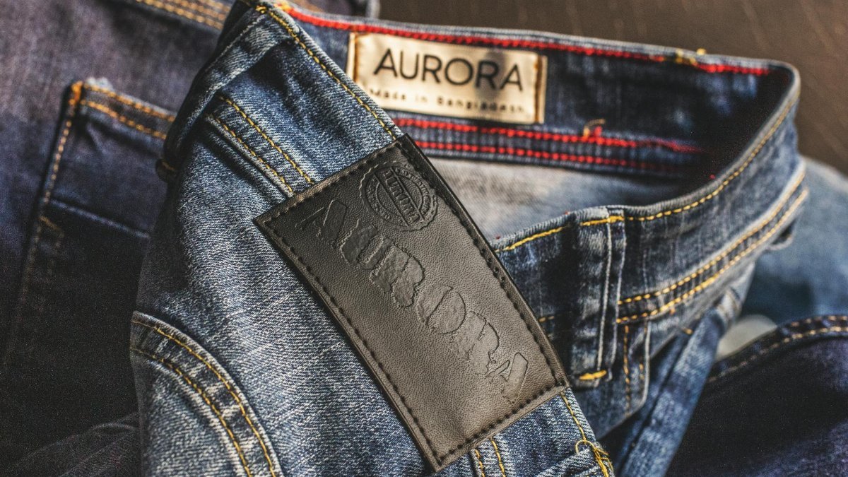 Close-up of blue denim jeans showcasing Aurora label, made in Bangladesh.