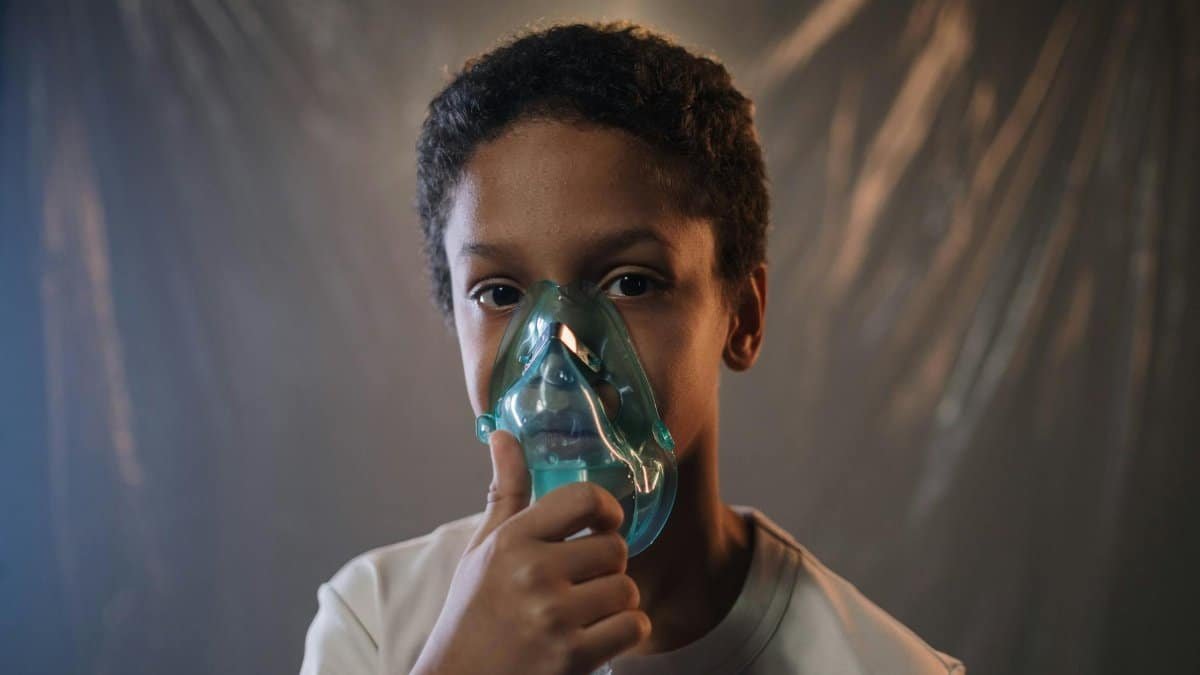 Portrait of a child using an oxygen mask indoors, highlighting health care needs.