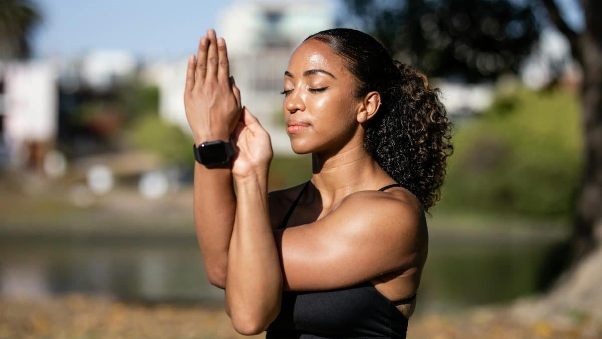 African American woman meditating outdoors, exuding relaxation and wellness.