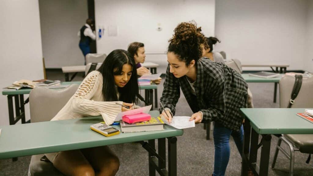 Two female students working together during a study session in a college classroom.