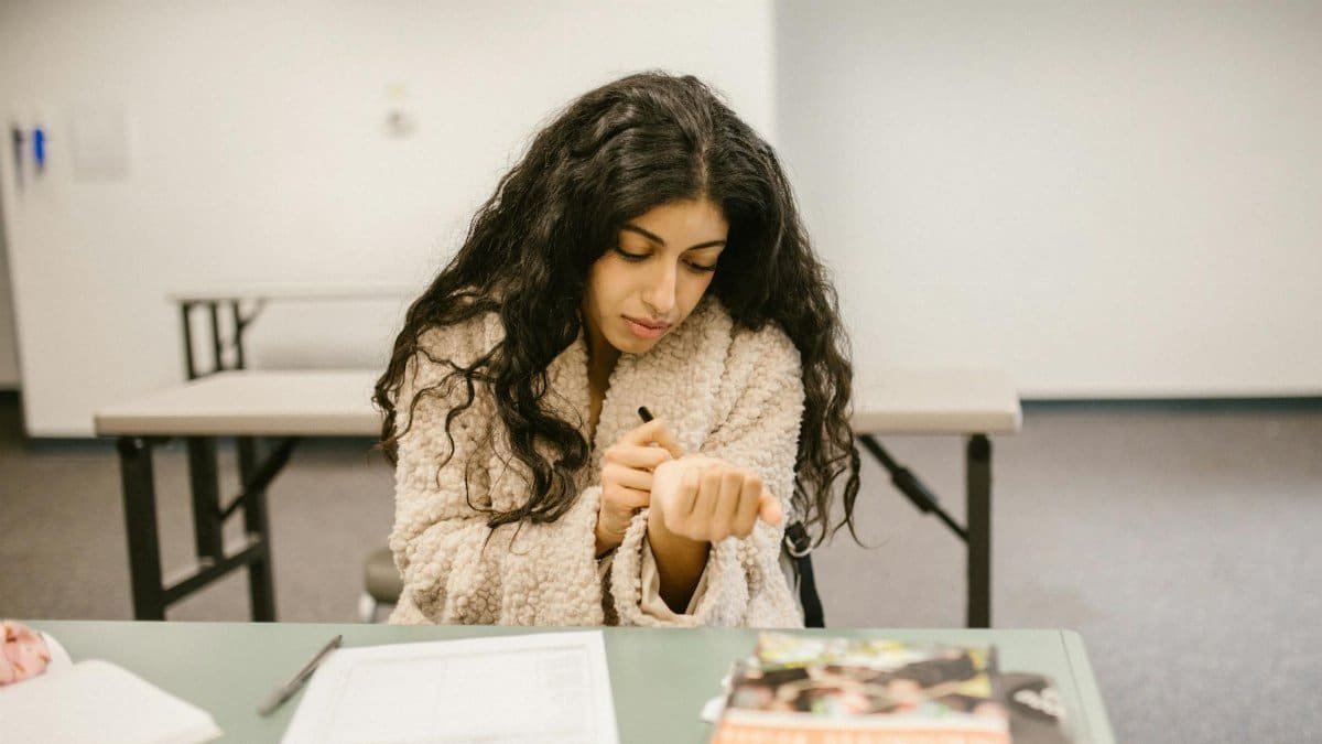 Female student discreetly cheating during an exam at school, showcasing the stress and pressures of academics.