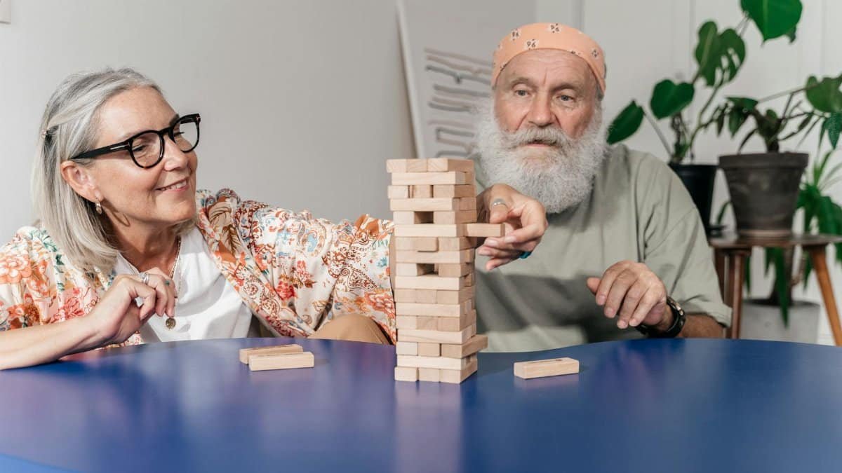 Elderly couple enjoying a game of Jenga indoors, showcasing bonding and leisure time.