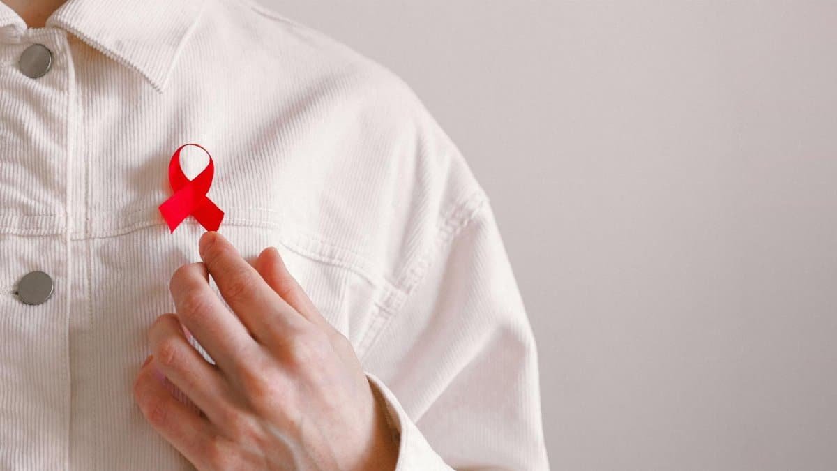 Close-up of a red ribbon on a white shirt symbolizing AIDS awareness and support.