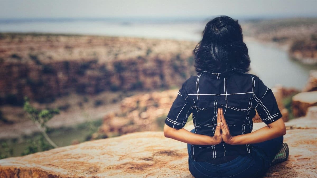 Woman practicing yoga on a cliff overlooking a canyon in India, promoting mindfulness and serenity.