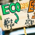 Close-up of a cardboard protest sign with 'Eco Not Ego' message at a climate rally.