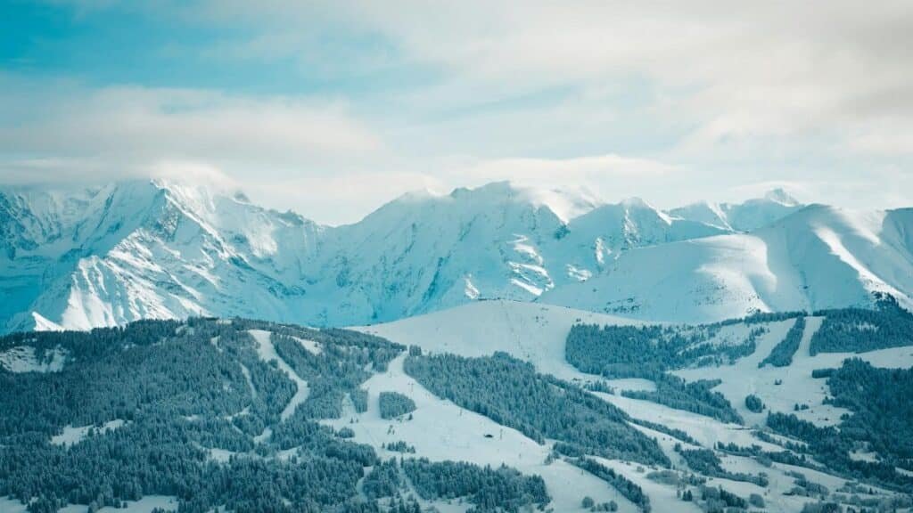 A serene winter landscape showcasing snow-covered mountains and forests in Megève, France.