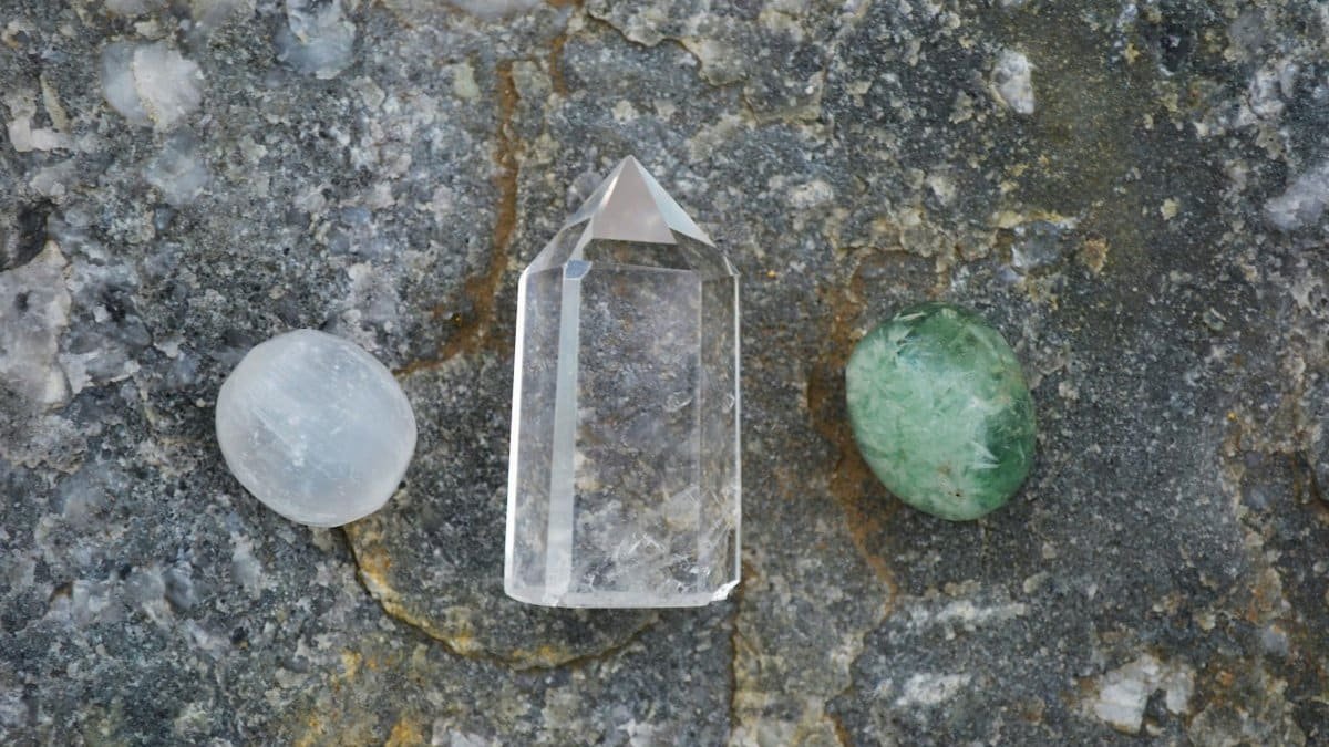 Assorted healing crystals including quartz on a textured stone surface.