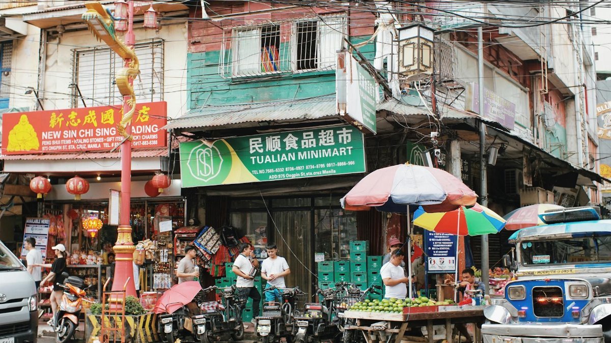 Vibrant market street in Manila's Chinatown with shops, vendors, and locals.