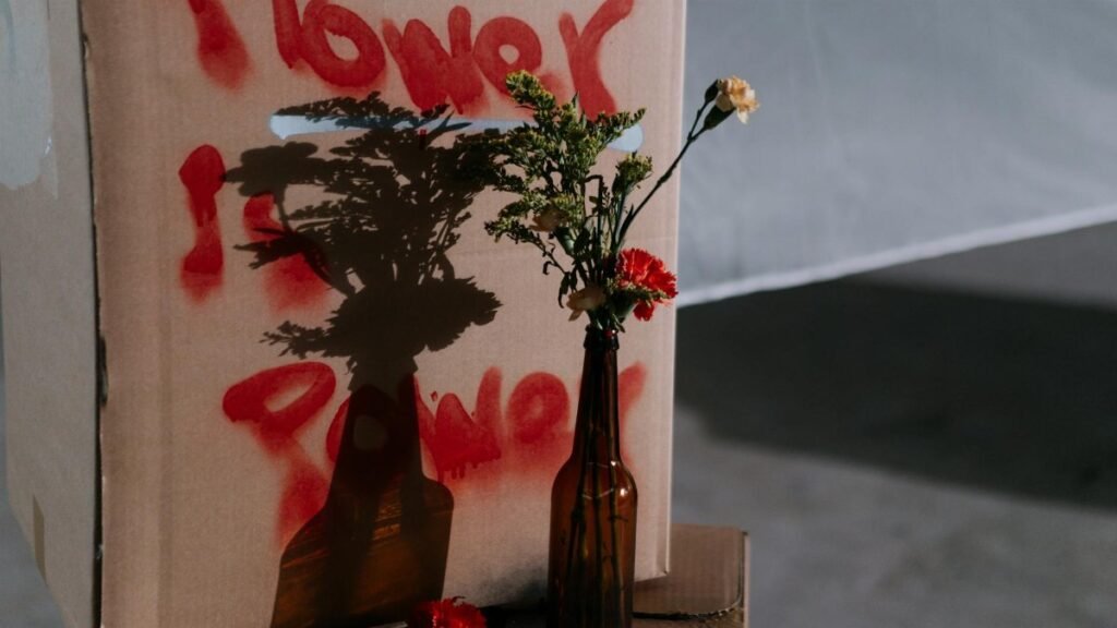A floral arrangement casts a shadow with 'Flower is Power' sprayed in red, symbolizing peaceful protest.