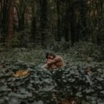 A calm moment captured with a woman sitting amidst lush greenery in a Portland forest.