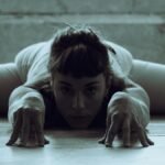 Artistic shot of a woman in a deep stretching pose on the floor.