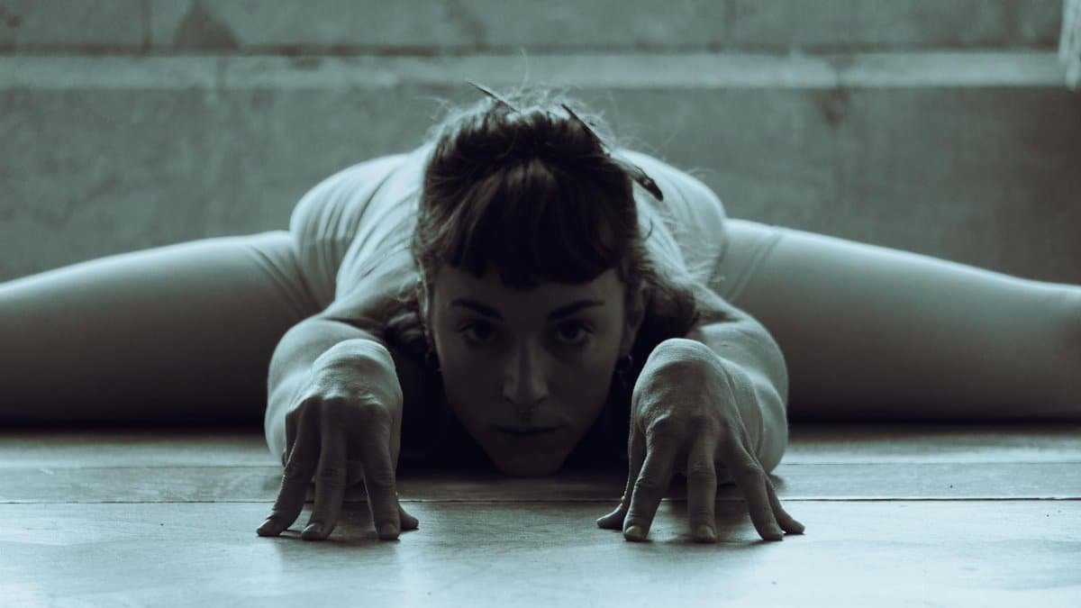 Artistic shot of a woman in a deep stretching pose on the floor.