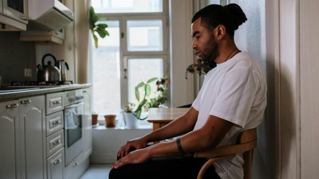 A thoughtful man sits quietly in the kitchen, reflecting and contemplating life indoors.