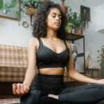 Calm woman in activewear meditating indoors, promoting a healthy lifestyle.