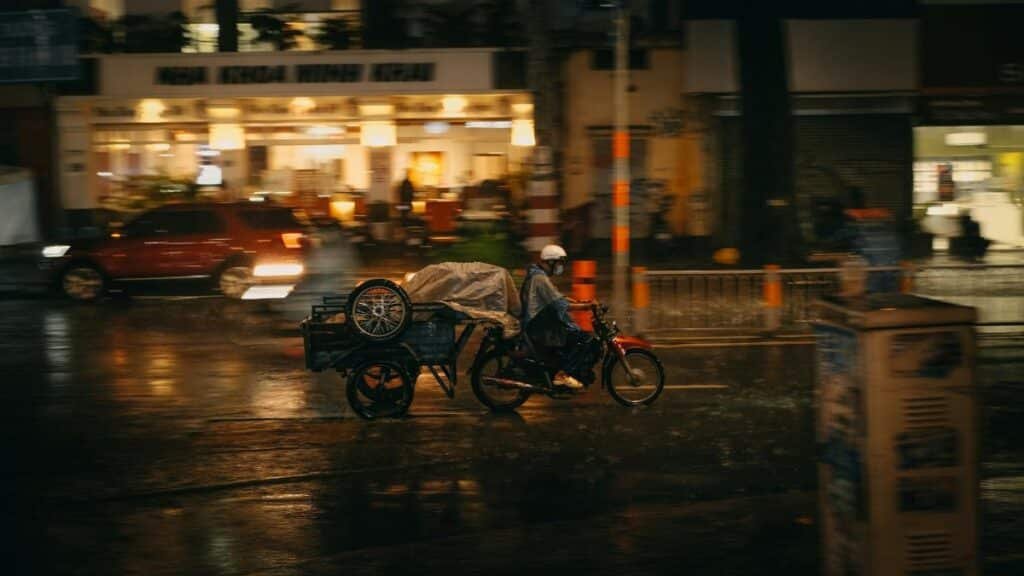 Person on a motorcycle rides through wet streets of Washington, DC at night, depicting urban life in the rain.