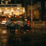 Person on a motorcycle rides through wet streets of Washington, DC at night, depicting urban life in the rain.