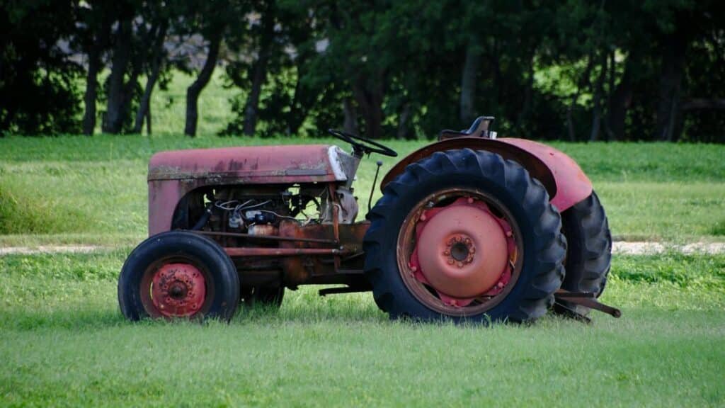 A rusty old tractor sits in a vibrant green field, reflecting rural San Antonio's agricultural charm.