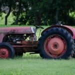 A rusty old tractor sits in a vibrant green field, reflecting rural San Antonio's agricultural charm.