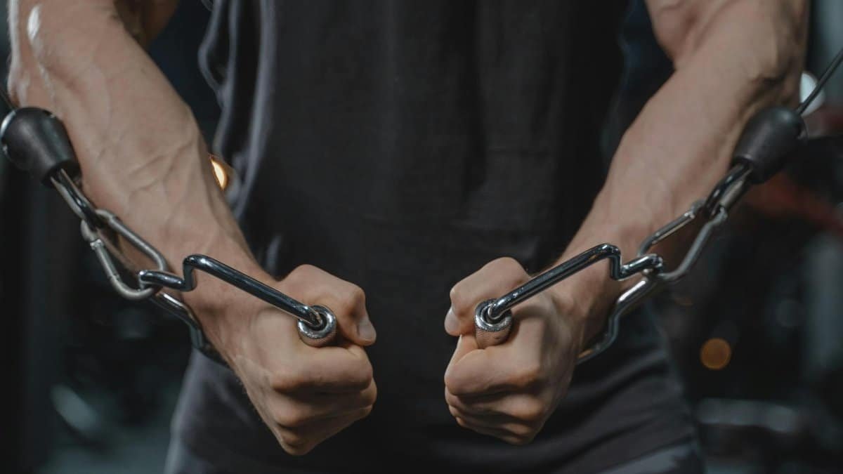 A muscular man exercising with a cable machine, emphasizing strength and fitness.