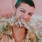 Young adult joyfully posing with a sparkly garland, embodying festive fun indoors.