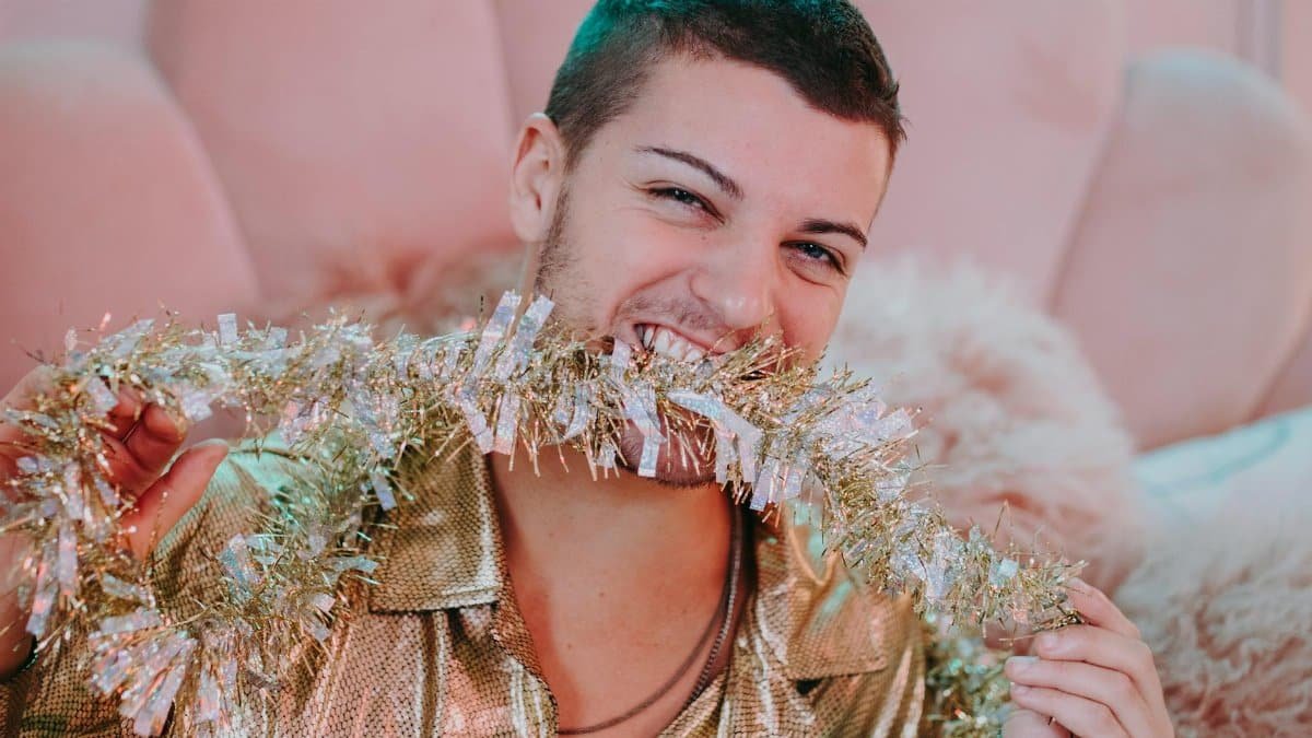 Young adult joyfully posing with a sparkly garland, embodying festive fun indoors.