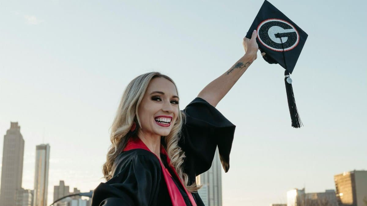 Joyful female graduate celebrating with cap in Atlanta skyline background.