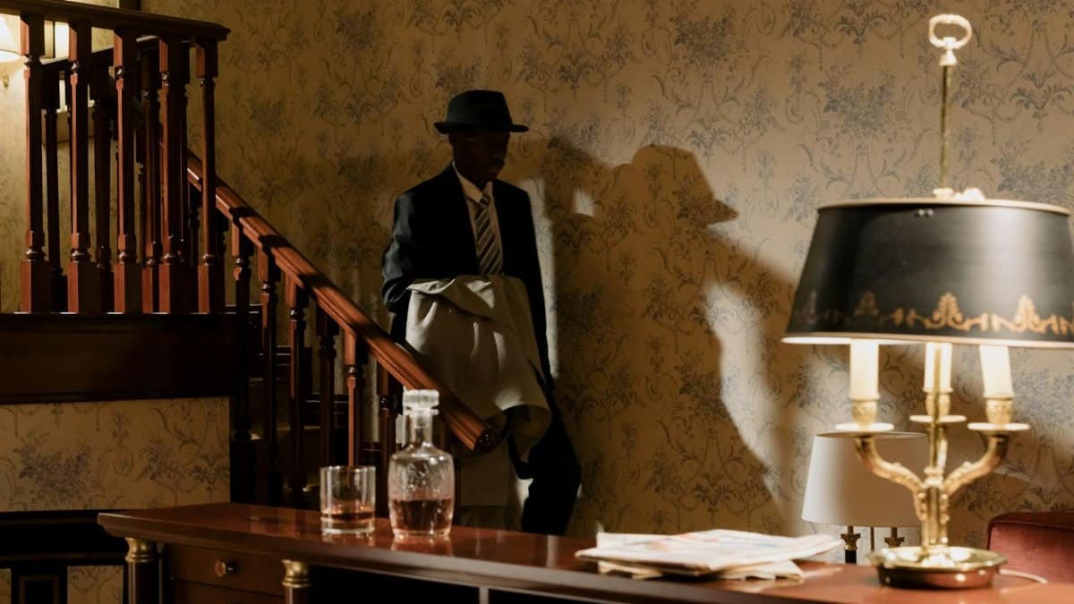 A shadowy detective in vintage attire descends wooden stairs, evoking a classic noir mood.