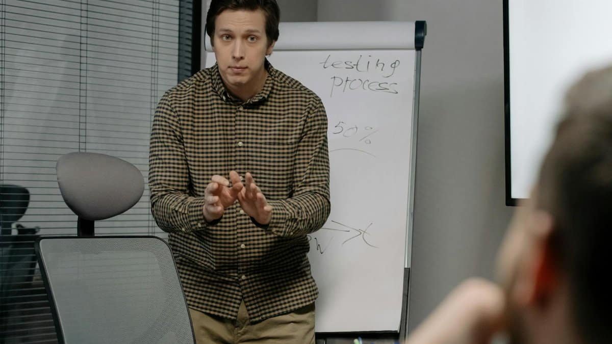 A man discusses testing processes during an office meeting with a focus on growth and strategy.