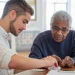 A young volunteer helps an elderly man manage his medication at a nursing home.