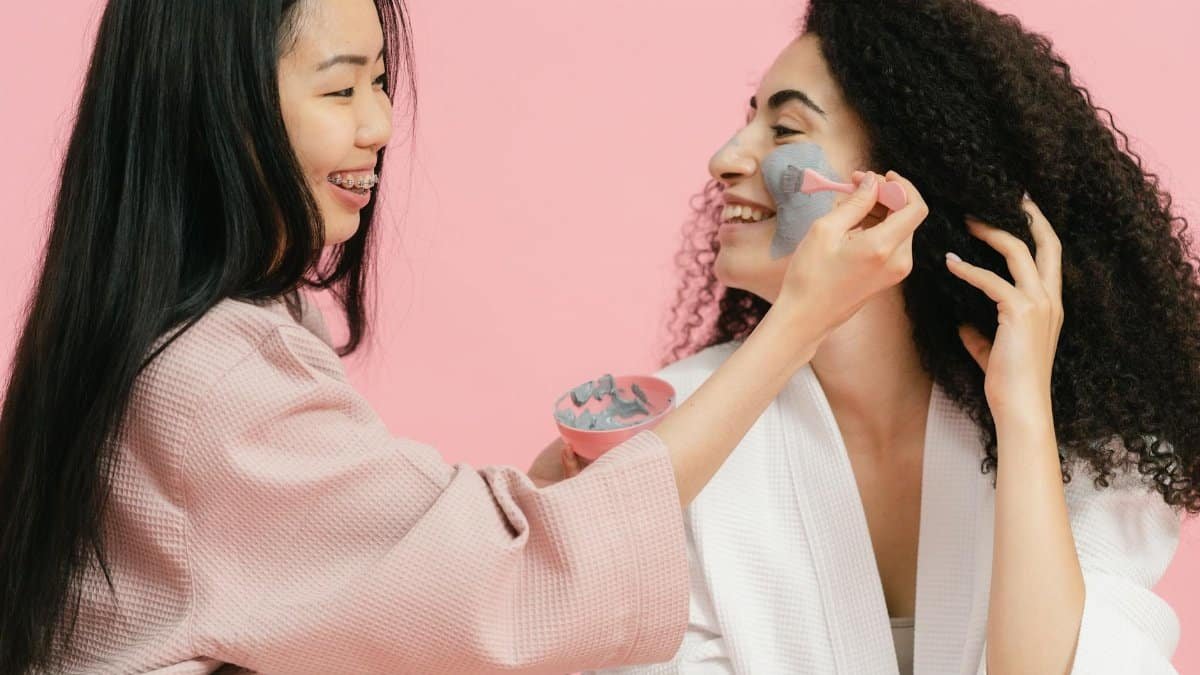 Two women having fun applying face masks and enjoying a skincare routine together.