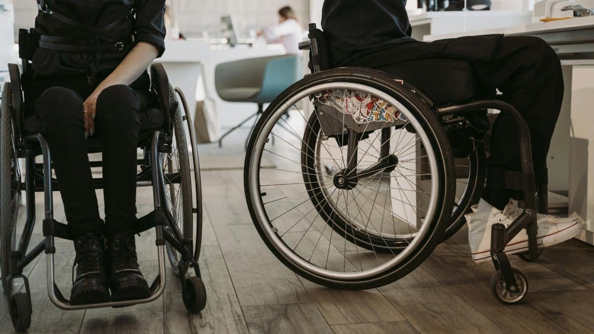 Two people in wheelchairs, indoors, symbolizing accessibility and modern workplace diversity.