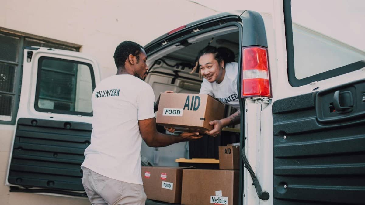 Volunteers unloading boxes of food and medicine from a van for community aid effort.