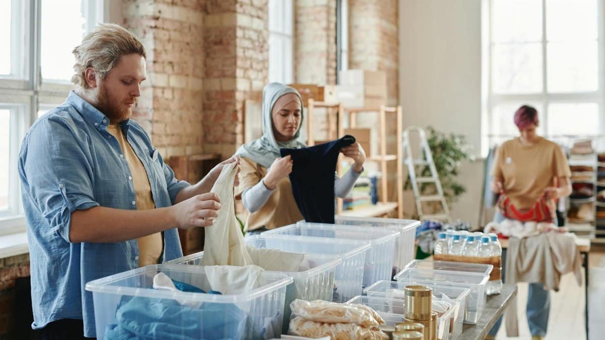 A diverse group of volunteers sorting clothes and goods in a well-lit loft.