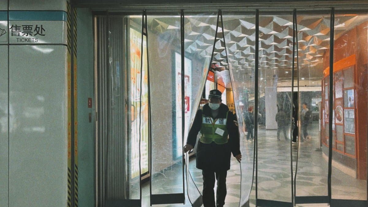Masked security guard entering Shanghai metro station, showcasing urban life.