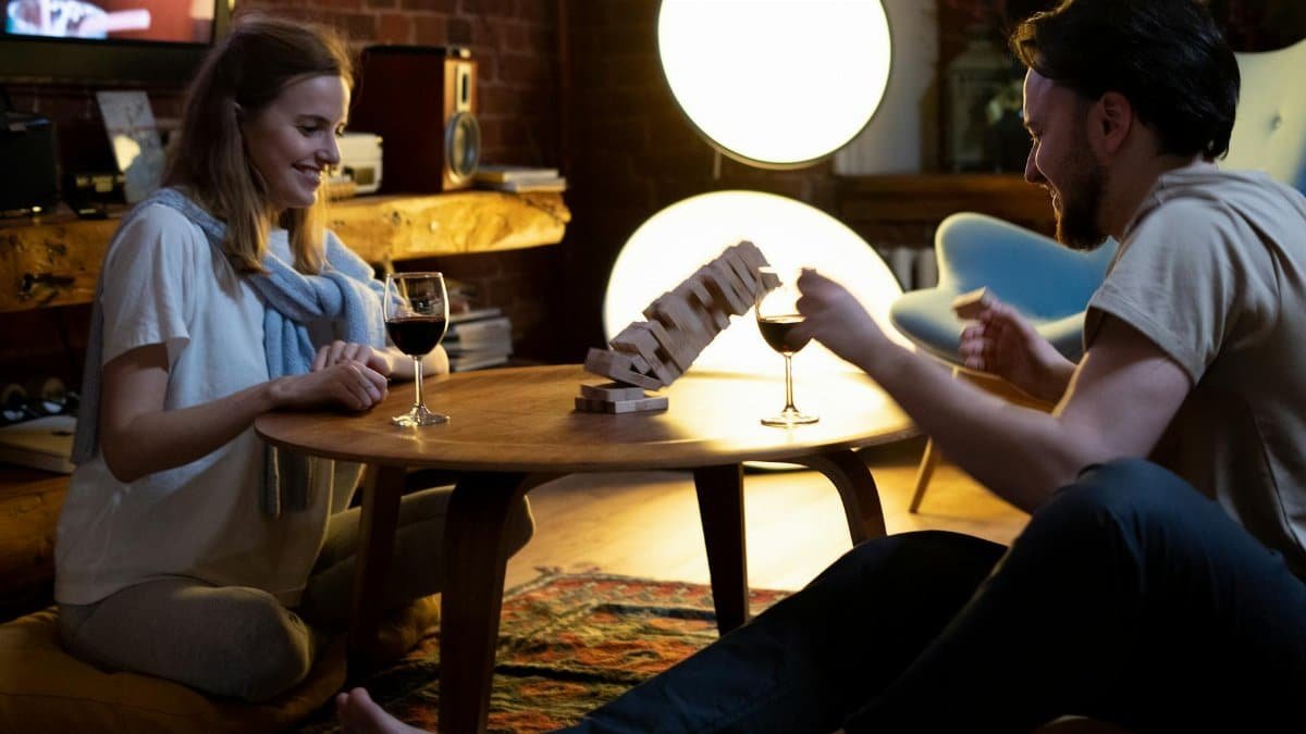 Couple enjoys a cozy evening playing a game with wine in a warm home setting.