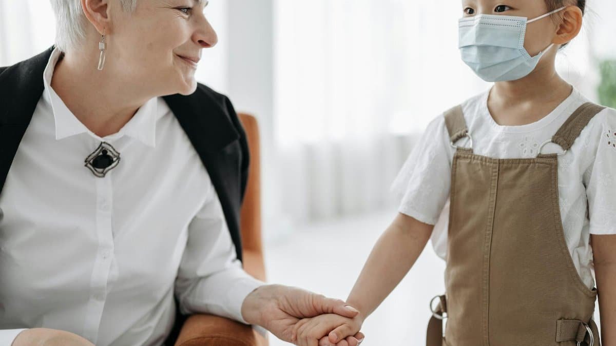 An adult and a child sharing a warm moment indoors, holding hands and smiling.