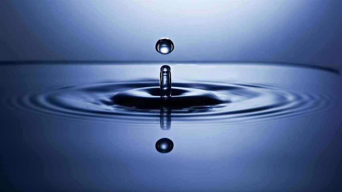 A mesmerizing close-up of a water droplet impact creating ripples on a smooth surface, captured in vibrant detail.